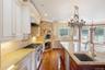 Kitchen with backsplash, light stone counters, hanging light fixtures, appliances with stainless steel finishes, and dark wood finished floors