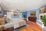 Bedroom with wood finished floors, crown molding, a fireplace, and a ceiling fan