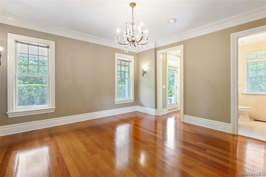 Unfurnished dining area featuring wood-type flooring, crown molding, and a chandelier