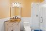 Bathroom with tile walls, a wainscoted wall, vanity, and a shower stall