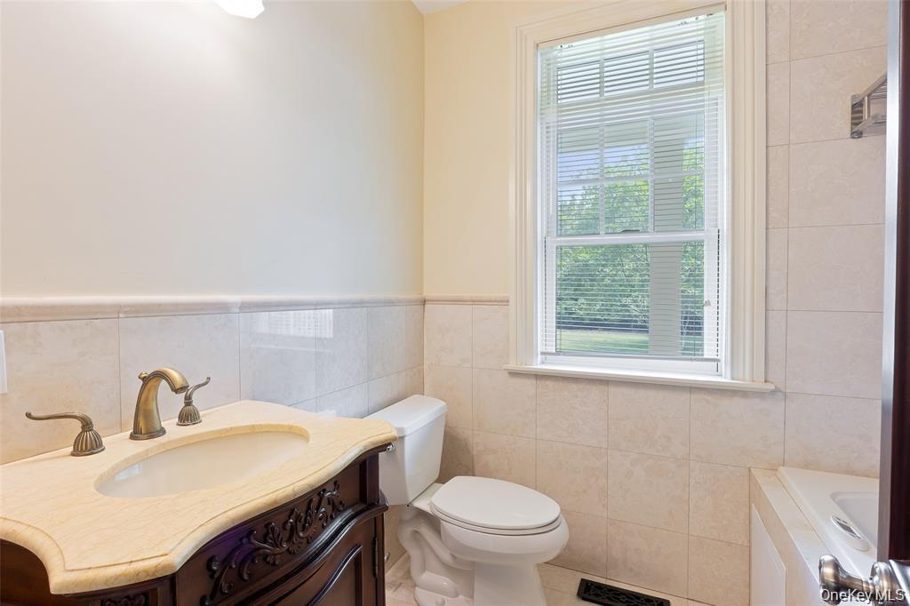 Bathroom with vanity, a garden tub, tile walls, wainscoting, and tile patterned floors
