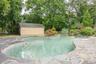 Outdoor pool with view of scattered trees, an outbuilding, and a patio area