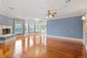 Unfurnished living room featuring ornamental molding, a high end fireplace, a chandelier, plenty of natural light, and wood finished floors