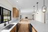Kitchen with light wood finished floors, light stone countertops, a warm lit fireplace, open floor plan, and beverage cooler