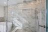 Bathroom with a freestanding bath, tile walls, and a marble finish shower