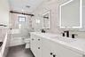 Full bath with tile walls, shower / bath combination with glass door, double vanity, and dark tile patterned flooring