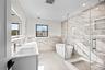 Full bath featuring tile walls, a freestanding tub, healthy amount of natural light, double vanity, and a marble finish shower