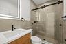 Bathroom with vanity, a shower stall, and tile walls