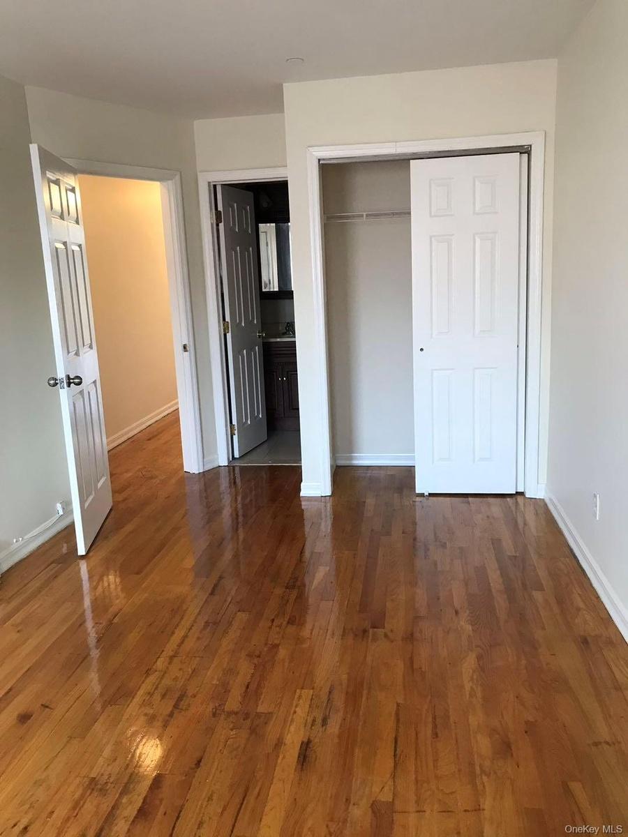 Unfurnished bedroom with dark wood-type flooring, a closet, and connected bathroom