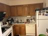 Kitchen with white appliances, brown cabinets, backsplash, light countertops, and exhaust hood