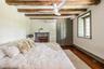 Bedroom with an AC wall unit, a baseboard heating unit, beam ceiling, dark wood-style floors, and ceiling fan
