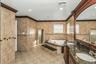 Full bathroom with a bath, tile walls, double vanity, recessed lighting, and ornamental molding