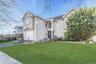 View of front of property featuring a front lawn, stucco siding, driveway, and a garage