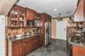 Kitchen featuring backsplash, granite tiled floors, stainless steel appliances, dark stone counters, and recessed lighting