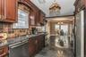 Kitchen featuring arched walkways, granite tiled floors, appliances with stainless steel finishes, hanging light fixtures, and decorative backsplash