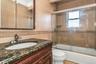 Full bath featuring enclosed tub / shower combo, vanity, ornamental molding, and tile walls