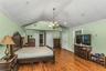 Bedroom with crown molding, wood finished floors, a chandelier, and lofted ceiling
