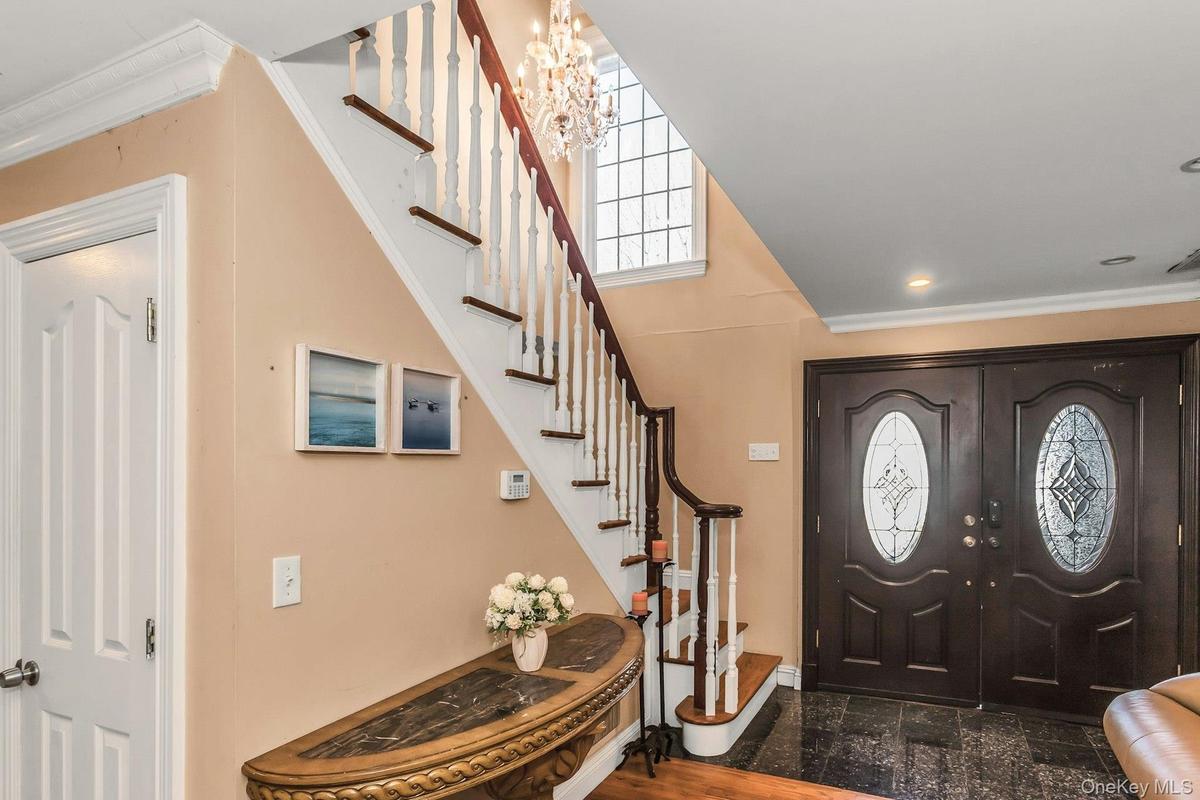 Entrance foyer with stairway, a chandelier, crown molding, and french doors