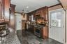 Kitchen with stainless steel appliances, crown molding, dark brown cabinetry, granite floors, and custom range hood