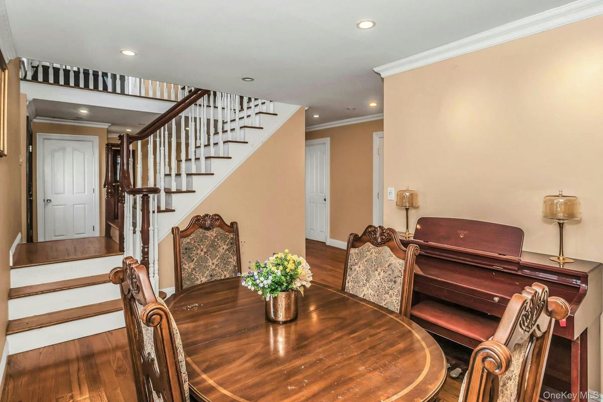 Dining space with wood finished floors, ornamental molding, stairs, and recessed lighting