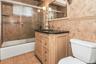 Bathroom with combined bath / shower with glass door, vanity, light tile patterned flooring, and tile walls