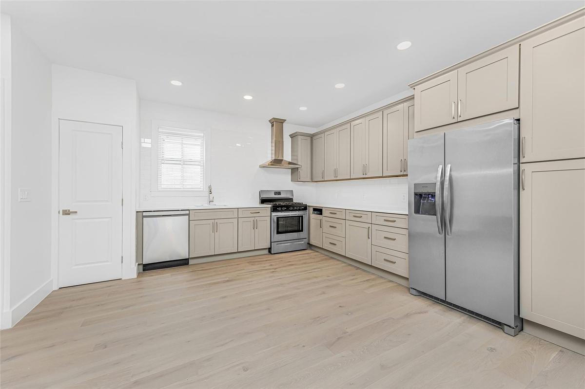 Kitchen featuring appliances with stainless steel finishes, wall chimney range hood, light wood-style flooring, light countertops, and recessed lighti