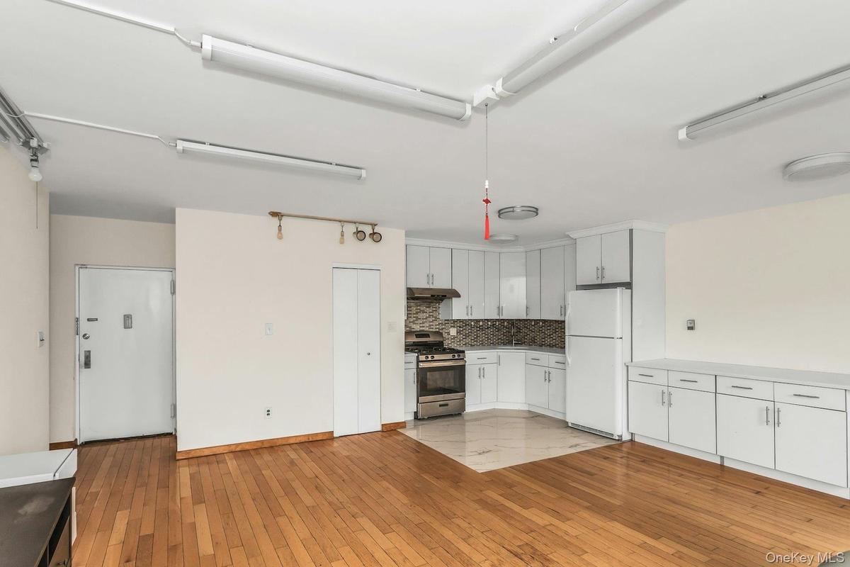 Kitchen featuring white cabinetry, freestanding refrigerator, gas range, light countertops, and light wood-style floors