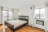 Bedroom featuring access to outside, light wood-type flooring, a wall unit AC, and a city view