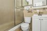 Bathroom with vanity, tile walls, and combined bath / shower with glass door