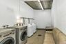 Shared laundry room with tile patterned floors, washer and dryer, and concrete block wall