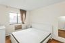 Bedroom featuring dark wood-type flooring, a baseboard heating unit, and a wall unit AC