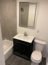 Bathroom featuring vanity, toilet, shower / tub combination, and wood tiled floors