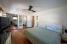 Bedroom with multiple closets, wood finished floors, cooling unit, and ceiling fan