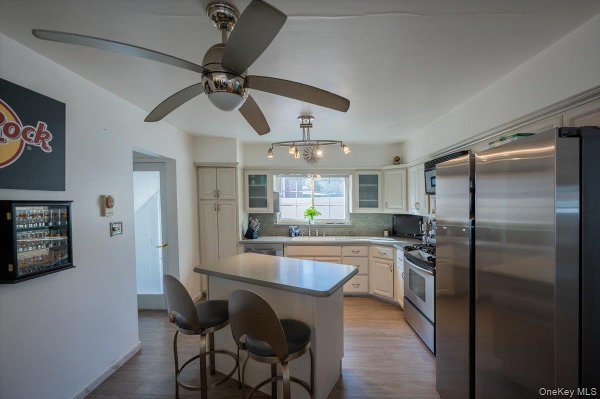 Kitchen featuring stainless steel appliances, tasteful backsplash, a kitchen island, a kitchen breakfast bar, and wood finished floors