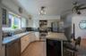 Kitchen featuring appliances with stainless steel finishes, a breakfast bar area, backsplash, light wood finished floors, and glass insert cabinets