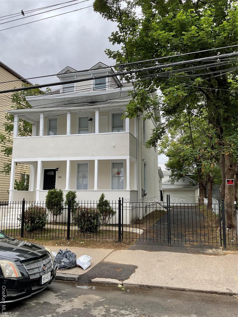 View of front of property with covered porch, stucco siding, a balcony, and a fenced front yard