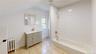 Bathroom with bathtub / shower combination, radiator heating unit, vanity, and light tile patterned flooring