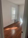 Unfurnished room featuring radiator, dark wood-style flooring, and baseboards