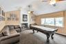 Living room featuring carpet flooring, a brick fireplace, ceiling fan, and pool table