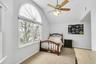 Bedroom featuring light colored carpet, multiple windows, lofted ceiling, and ceiling fan