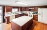 Kitchen with white appliances, dark wood-style floors, light countertops, and dark brown cabinets
