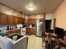 Kitchen with brown cabinetry, freestanding refrigerator, white electric range, light countertops