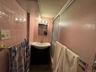 Full bathroom featuring a shower stall, tile walls, vanity, and dark tile patterned floors in the landlords apartment.