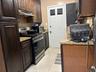 Kitchen with stainless steel appliances, light stone counters, light tile patterned floors, and under cabinet range hood
