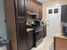 Kitchen featuring appliances with stainless steel finishes, decorative backsplash, light stone counters, and light tile patterned floors
