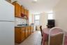Kitchen with white appliances, backsplash, dark countertops, light tile patterned floors, and brown cabinets