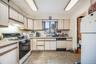 Kitchen featuring white cabinets, sink, and white appliances