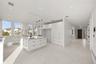 Kitchen featuring modern cabinets, hanging light fixtures, white cabinetry, a kitchen island, and light stone countertops