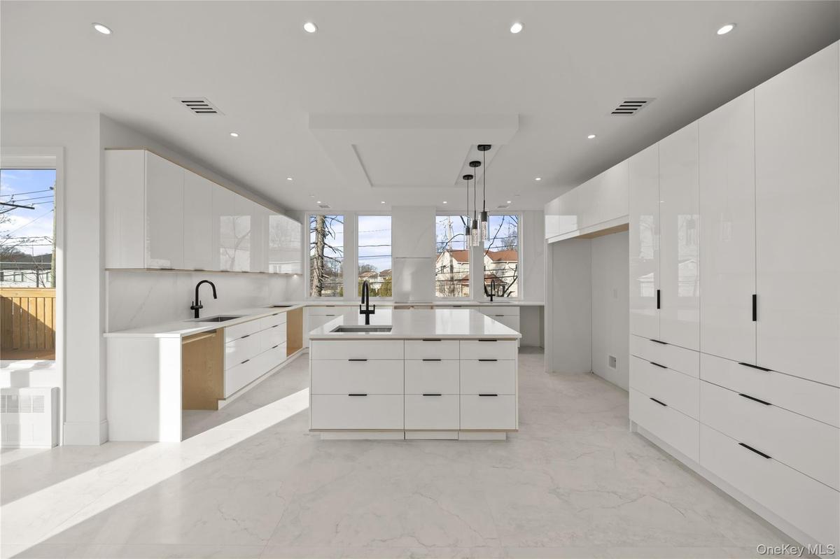 Kitchen with modern cabinets, white cabinetry, decorative light fixtures, light marble finish floors, and light stone countertops