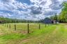 View of yard featuring a barn, a view of rural / pastoral area, an outdoor structure, and a wooded view